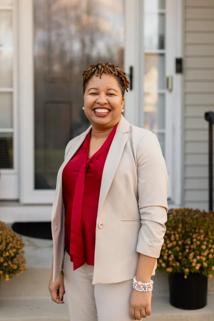 Smiling person standing in front of house.