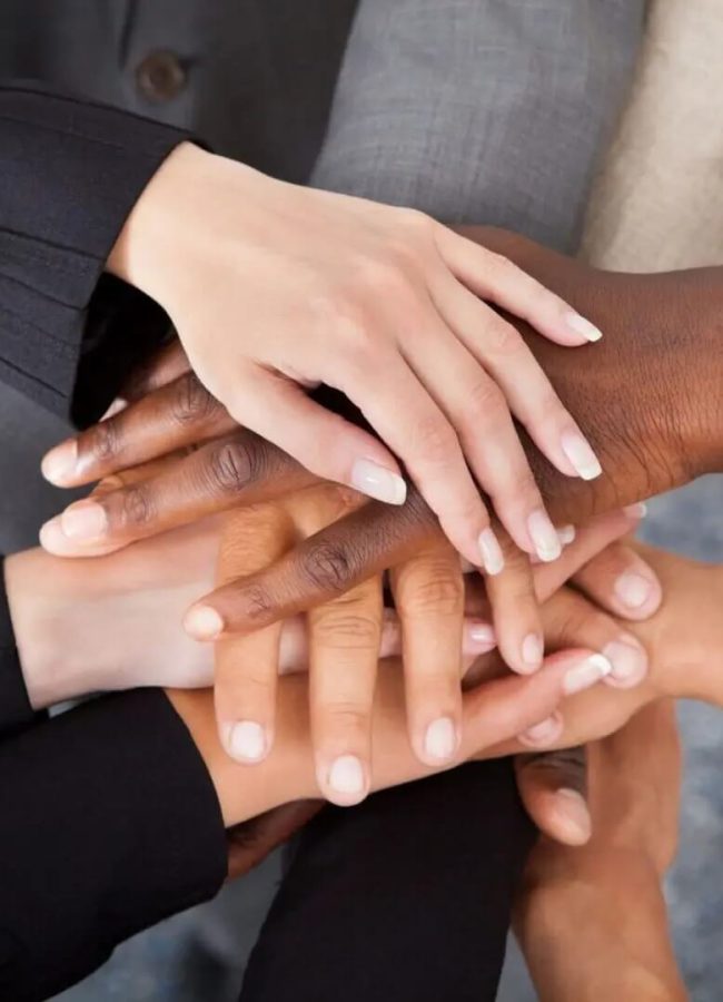 Diverse hands stacked in unity gesture.